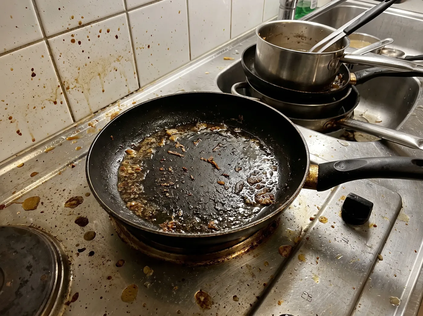 Greasy hob and a stack of dirty pans after frying